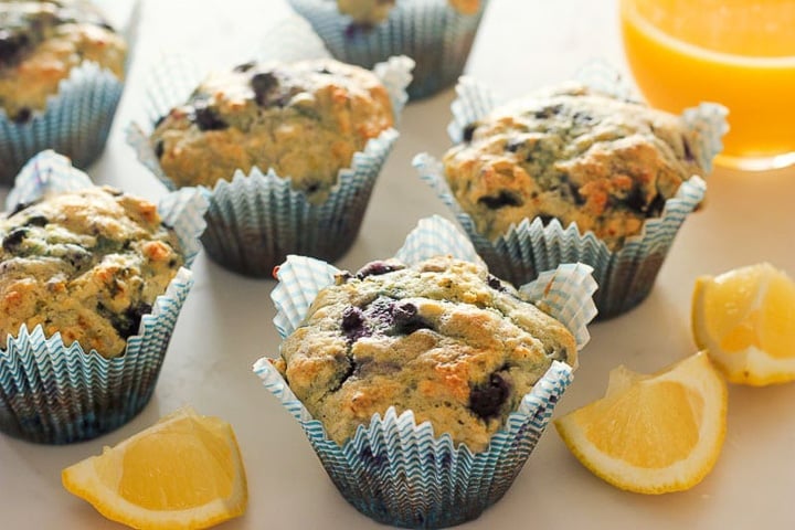 Blueberry lemon muffins with lemon wedges and glass of orange juice