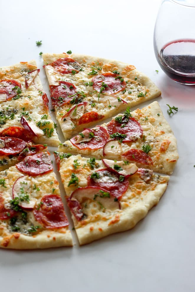Pizza with blue cheese, apple, spicy salami and glass of red wine