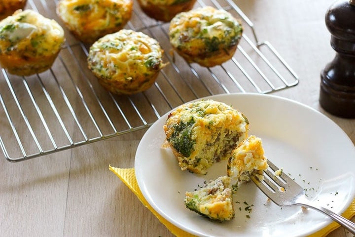 Egg, sausage parsley muffins cooling on rack, one on plate with fork
