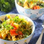 Two bowls of fusilli pasta with peppers and parsley