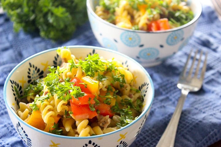 Two bowls of fusilli pasta with peppers and parsley