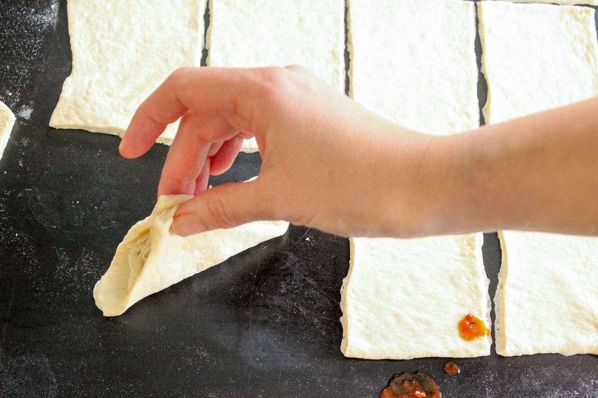 Square of pizza dough with opposite corners pinched together