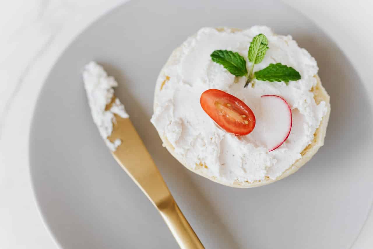 Goat cheese smeared on bread with knife