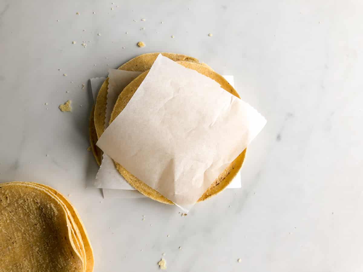 Stack of corn tortillas layered with parchment paper between them