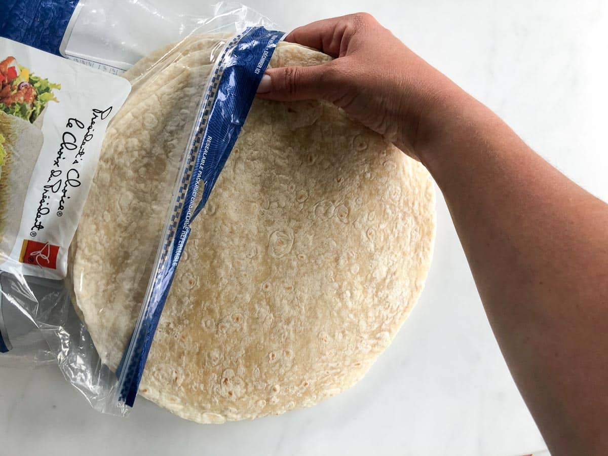 Hand taking large flour tortillas out of bag