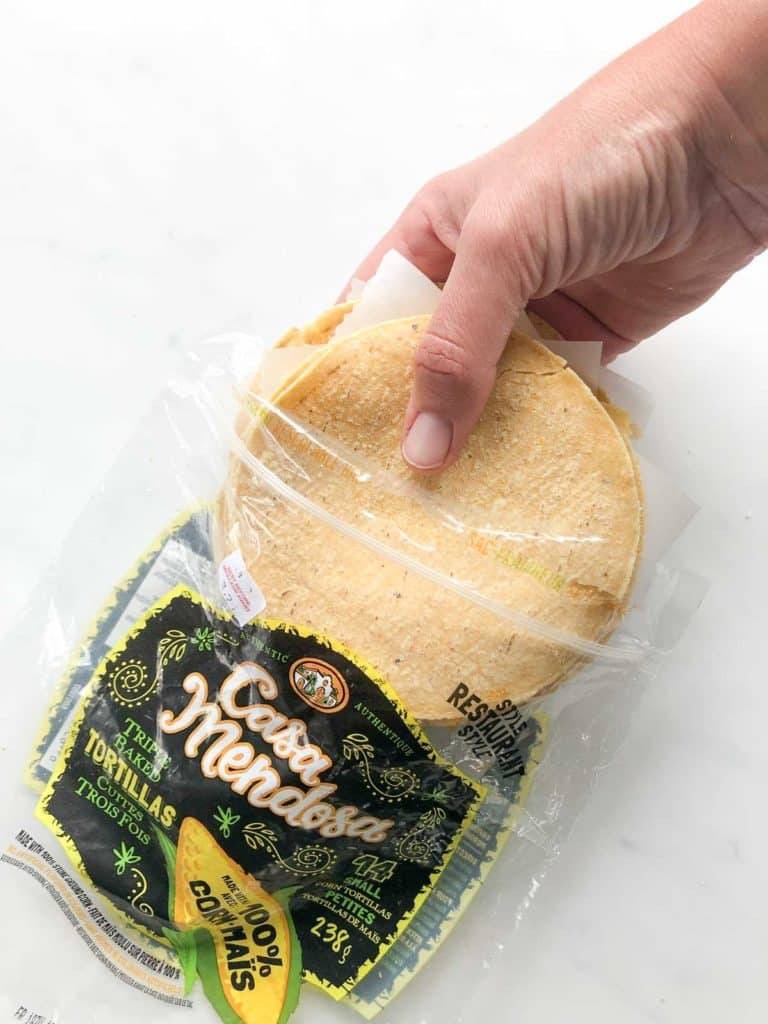 Bag of corn tortillas with a hand removing the tortillas