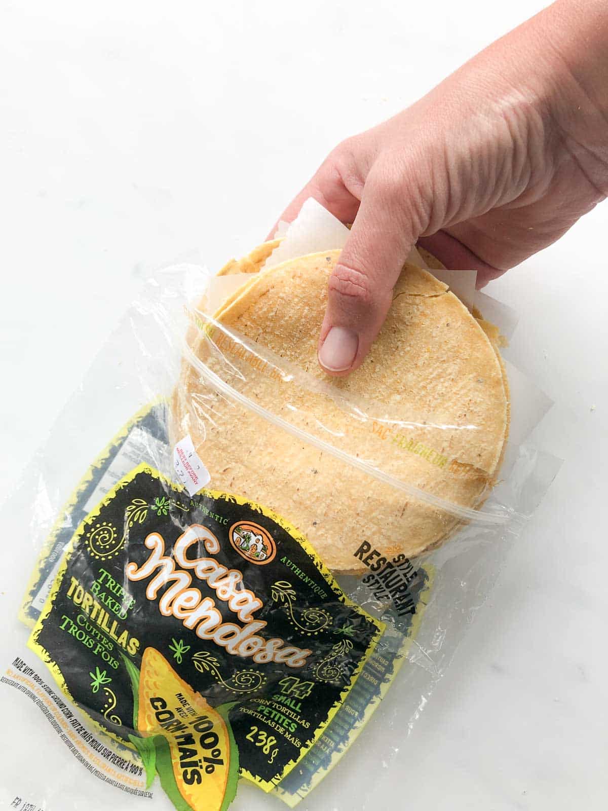 Bag of corn tortillas with a hand removing the tortillas