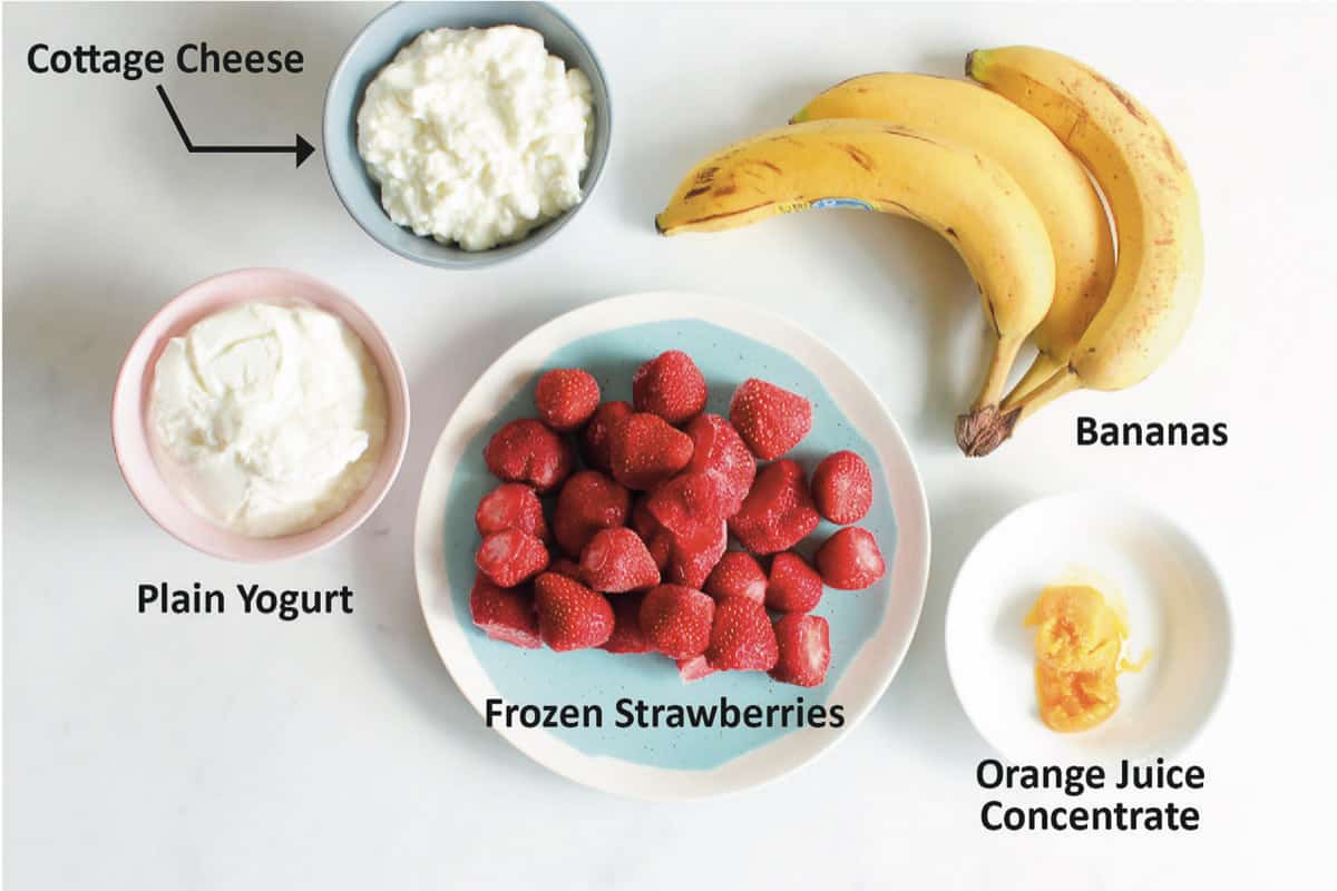Bowl of cottage cheese, bowl of plain yogurt, plate of frozen strawberries, three bananas, spoonful of orange juice concentrate