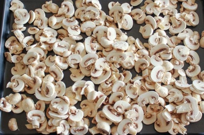 Sliced mushrooms on metal sheet pan.