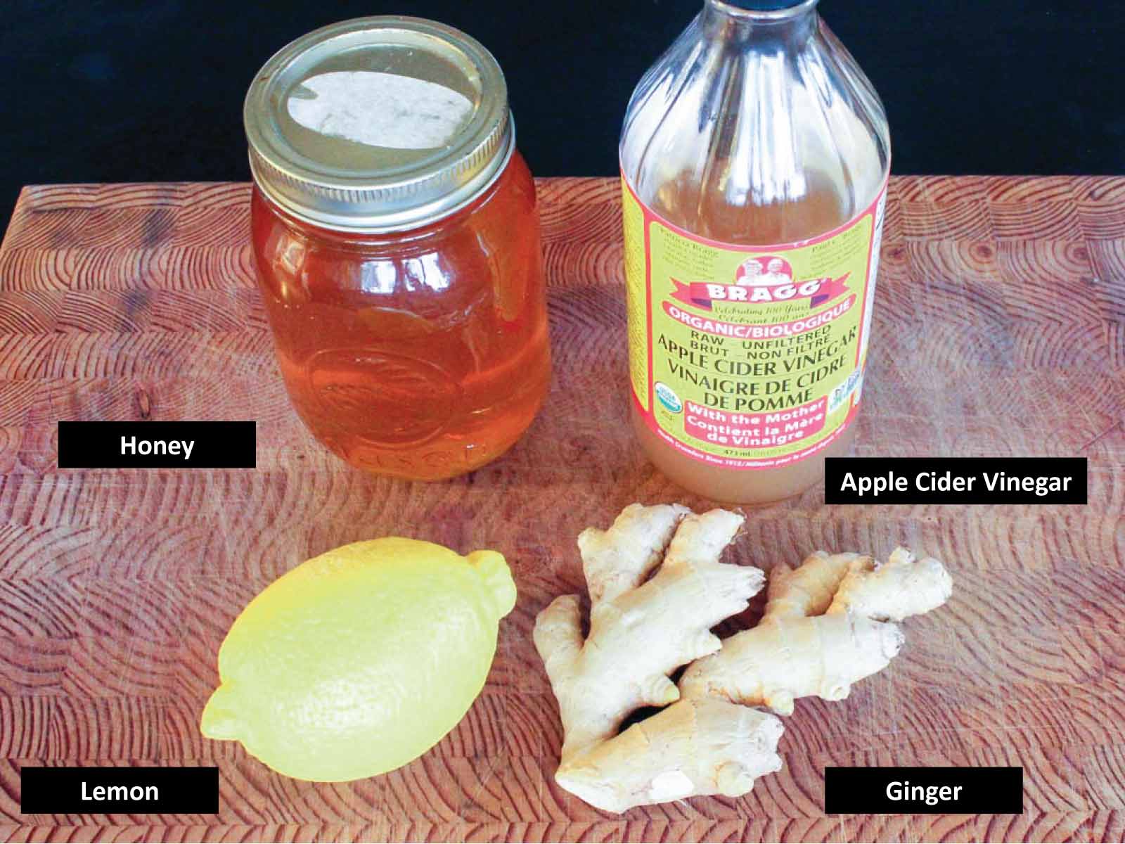 Cutting board with the following labelled ingredients: honey, apple cider vinegar, lemon, ginger root